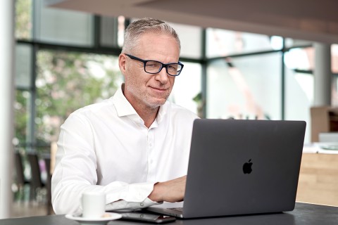 Mann arbeitet am Macbook in einem Cafe